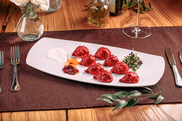 Portion of gourmet red colored dumplings with sauce