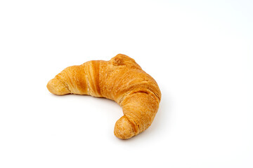 A croissant is on a white background. It is brown and has a curved shape. The croissant is not cut in half
