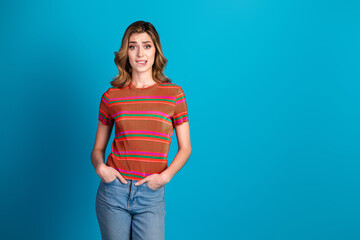 Young woman in casual striped t-shirt posing against vibrant blue background, showcasing cheerful...