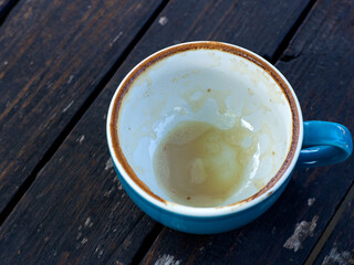 Coffee that has been finished. An empty mug of coffee on a black wooden table. Dirty mug.