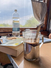Enjoying coffee and book on train journey with water and biscuits