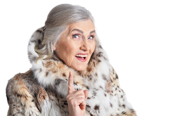portrait of beautiful senior woman in fur coat pointing up