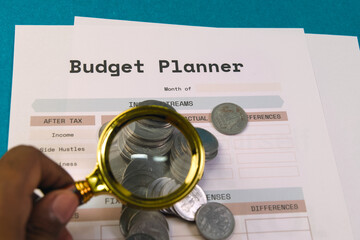 Budget planner with coins and a magnifying glass on a table