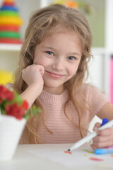 cute girl in the nursery draws at the table