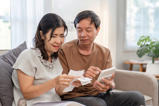 Elderly Couple Managing Family Finances at Home with Tablet and Documents for Budget Planning and Expense Tracking