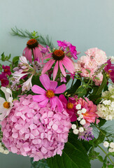 A bouquet of summer flowers in the room. Hydrangea, rose, echinacea, mint, snapdragon, asparagus and other flowers.