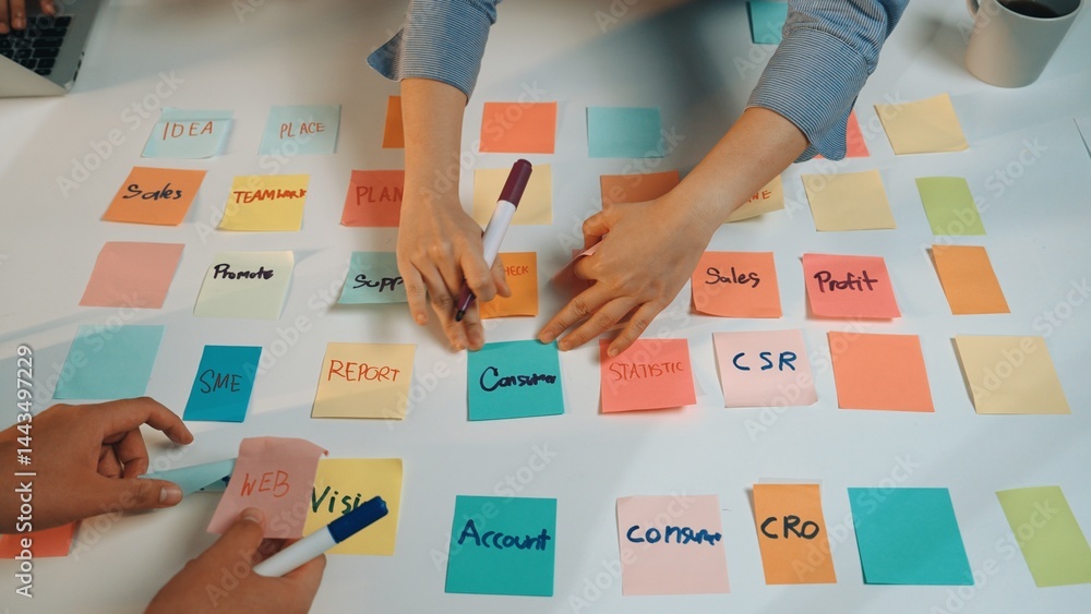 Poster hands writing on colorful sticky notes during a collaborative brainstorming session in an office. th