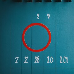 Close-up of a calendar page with a handwritten date highlighted in red, showcasing organization and planning.