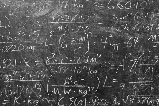 Wide blackboard inscribed with scientific formulas and calculations in physics, mathematics and electrical circuits. Science and education background.