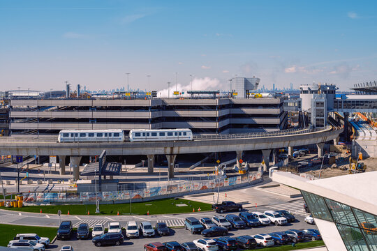 JFK Airport AirTrain Approaching Terminal with Parking Structure and City Skyline