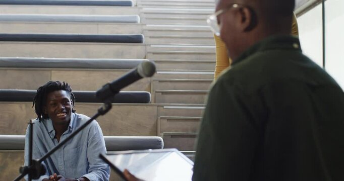 African American coworkers exchanging framed certificate in indoor stairwell, sharing recognition