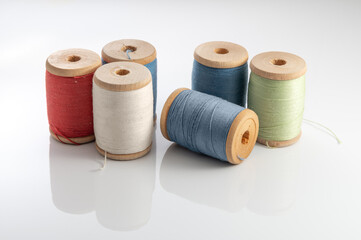 Six spools of vintage sewing thread in various colors sit on a white background. The spools have...