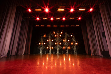 Symmetrically lit stage featuring red overhead and white LED backdrop lights, framed by deep blue curtains, creating a striking contrast on a polished floor.