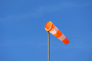 Orange and white striped windsock against a blue sky. A simple instrument to determine wind force...