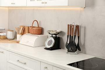 Retro mechanical kitchen scale and other utensils on white marble countertop indoors
