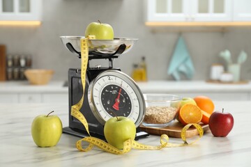 Kitchen scales with fruits, measuring tape and oatmeal in bowl on light marble table indoors