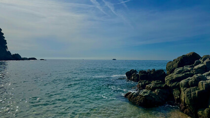 Sunlit beach in Lloret de Mar with and foamy waves. Picturesque scene perfect for lifestyle, relaxation, or wanderlust concepts.