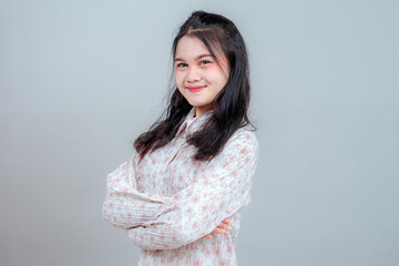 Portrait of a young Asian woman confidently smiling with arms crossed, expressing self-assurance...