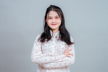 Portrait of a young Asian woman confidently smiling with arms crossed, expressing self-assurance...