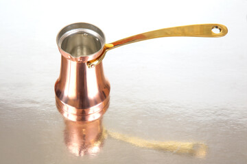 Close-up of a traditional copper Turkish coffee pot with a long brass handle, isolated on a white background, perfect for cultural beverage themes