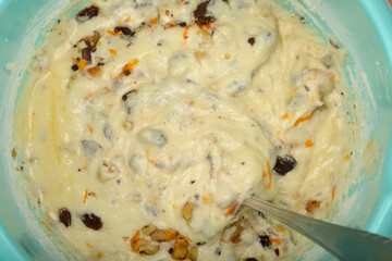 An overhead close-up shows a light blue mixing bowl filled with white meringue cake batter...