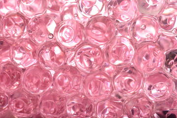 A macro close-up reveals a dense cluster of translucent pink gel beads, showing their round shapes and internal reflections