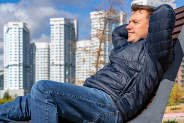 Urban Relaxation: A Man Enjoys Downtime on Bench with Cityscape
