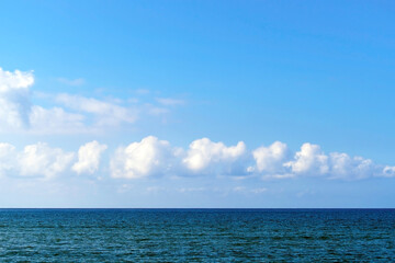 Fototapeta premium Blue sky with white cumulus fluffy cloud sea beach skyline. Morning beautiful sunlight nature seascape.