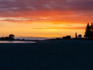 Fototapeta premium Intense sky sunrise colours along Mount Maunganui Main Beach