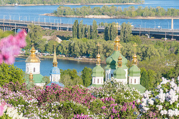 Foreground features church complex with multiple domes, largest one ornate and gold-accented,...