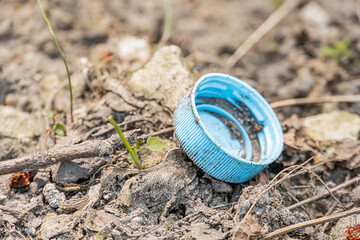 Plastic blue container partially buried in soil, small rocks, light-colored pathroad, outdoor scene, rocky terrain, natural lighting, realistic style, environmental subjects