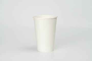 Light gray surface with a ridged white coffee cup in front view, open top and smooth surfaces.