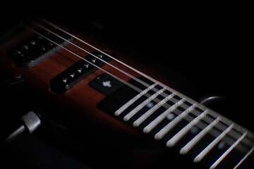 Close-up view of a dark electric guitar, with focus on the neck featuring frets and fret markers...