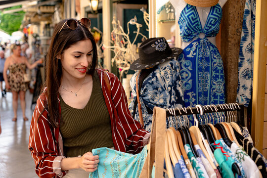 Tourist buying clothes in a street market stall, shopping for local handmade products during summer vacation