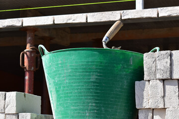 Building bricks next to mortar tub with masonry trowel on construction site