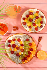 Kitchen background with fruit salads with soft grain cottage cheese, yogurt, dragon fruit, kiwi, mango, oranges, nuts, orange juice and grapes. Healthy light breakfast with ingredients