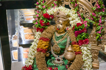 Fototapeta premium Goddess statue adorned with flowers in temple setting