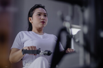 Dedicated Female Athlete Engages in Rowing Machine Workout Routi
