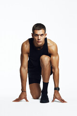 Determined young male gearing up for a sprint in a studio, embodying strength and focus, isolated against white background. Ideal for fitness marketing and motivational content.