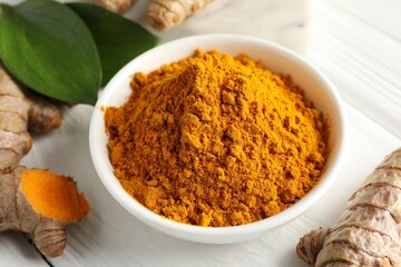 Aromatic turmeric powder, fresh roots and leaves on white wooden table, closeup