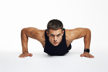 Fit young male performs focused push ups in a sleek studio space, showcasing strength and determination, isolated against white background. Ideal for fitness branding and workout marketing campaigns.