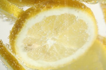 Soda water with lemon slices as background, closeup