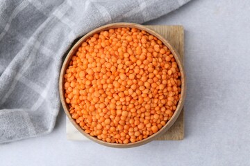 Red lentils in bowl on light table, top view