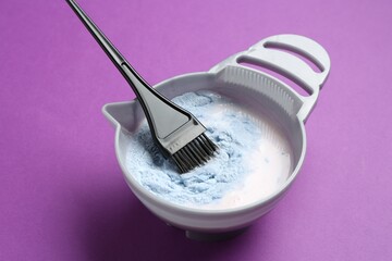 Mixing hair bleaching powder and developer on purple background, closeup