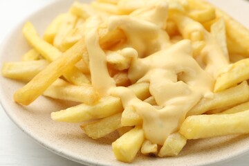 French fries with cheese sauce on table, closeup