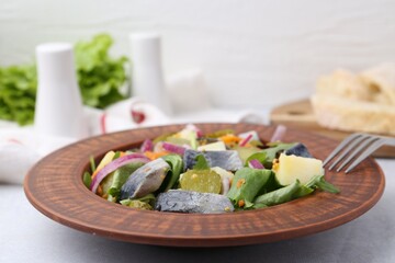 Delicious salad with herring and vegetables on light grey table, closeup