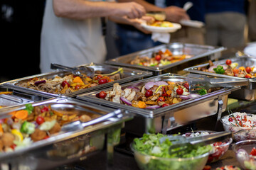Catering buffet featuring assorted colorful vegetables and salads at a gathering with guests...
