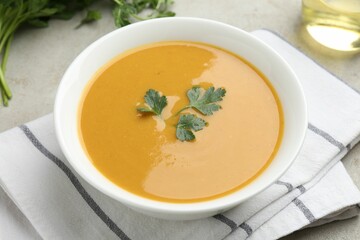 Delicious lentil cream soup with parsley and oil on light grey table, closeup