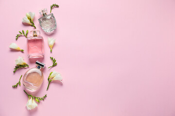 Bottles of perfume and beautiful flowers on pink background, flat lay. Space for text