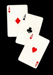 A hand of three playing cards of the same value isolated on a black background.